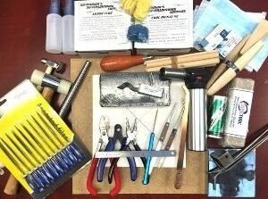 Assorted jewelry-making tools and materials arranged on a dark surface